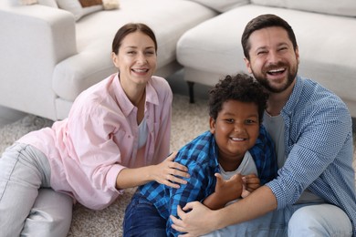 Photo of Adoption. Happy parents with their son on floor at home