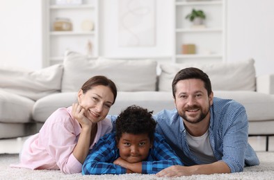 Photo of Adoption. Happy parents with their son on floor at home