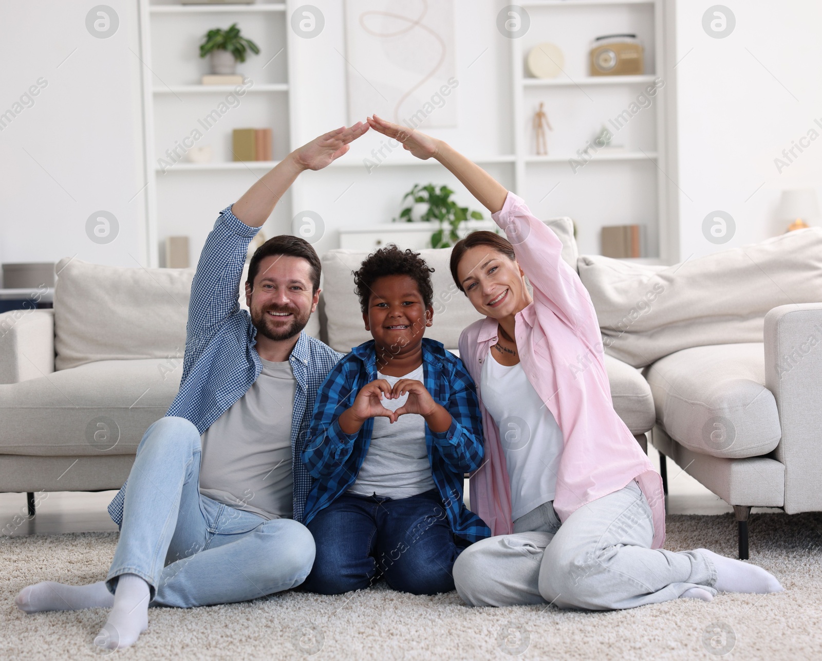 Photo of Adoption. Happy parents covering their son on floor at home