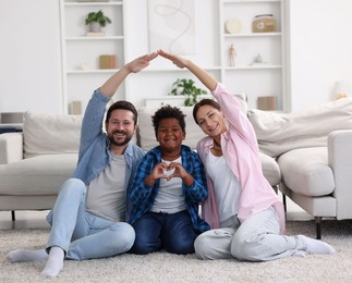 Photo of Adoption. Happy parents covering their son on floor at home