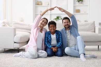 Photo of Adoption. Happy parents covering their son on floor at home