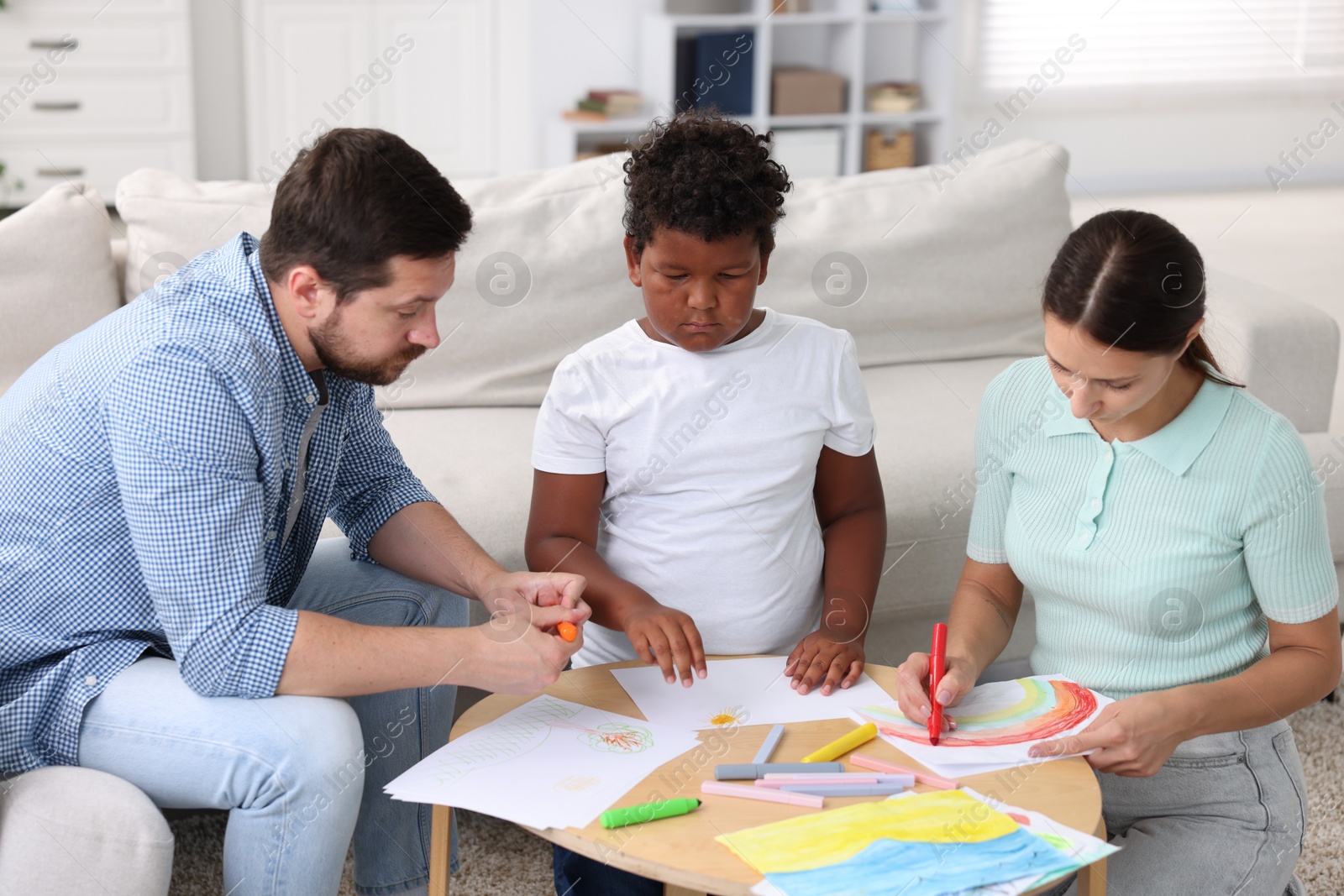 Adoption. Parents and their son drawing together at table indoors Photo of Adoption. Parents and their son drawing together at table indoors