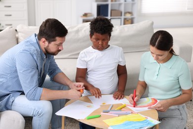 Photo of Adoption. Parents and their son drawing together at table indoors