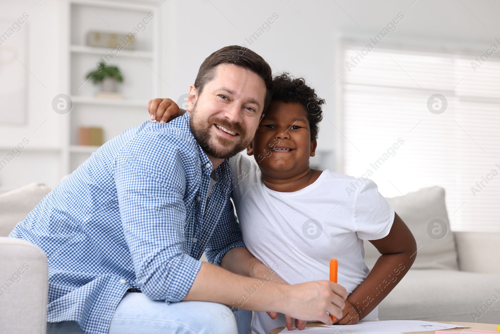 Adoption. Father and his son drawing together at table indoors Photo of Adoption. Father and his son drawing together at table indoors