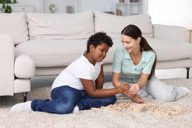 Photo of Adoption. Mother and her son playing with wooden blocks on floor at home