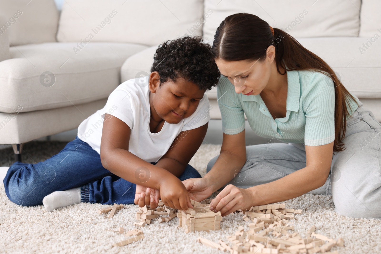 Photo of Adoption. Mother and her son playing with wooden blocks on floor at home