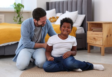 Photo of Adoption. Father and his son on floor at home