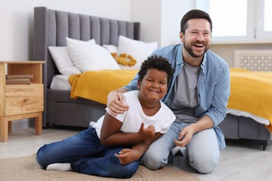 Photo of Adoption. Father and his son on floor at home