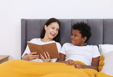 Photo of Mother reading fairy tale to her son at home