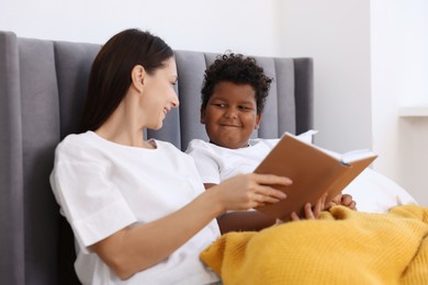 Photo of Mother reading fairy tale to her son at home