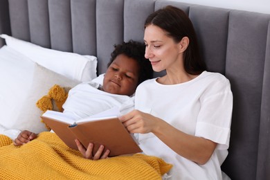 Photo of Mother reading fairy tale to her son at home