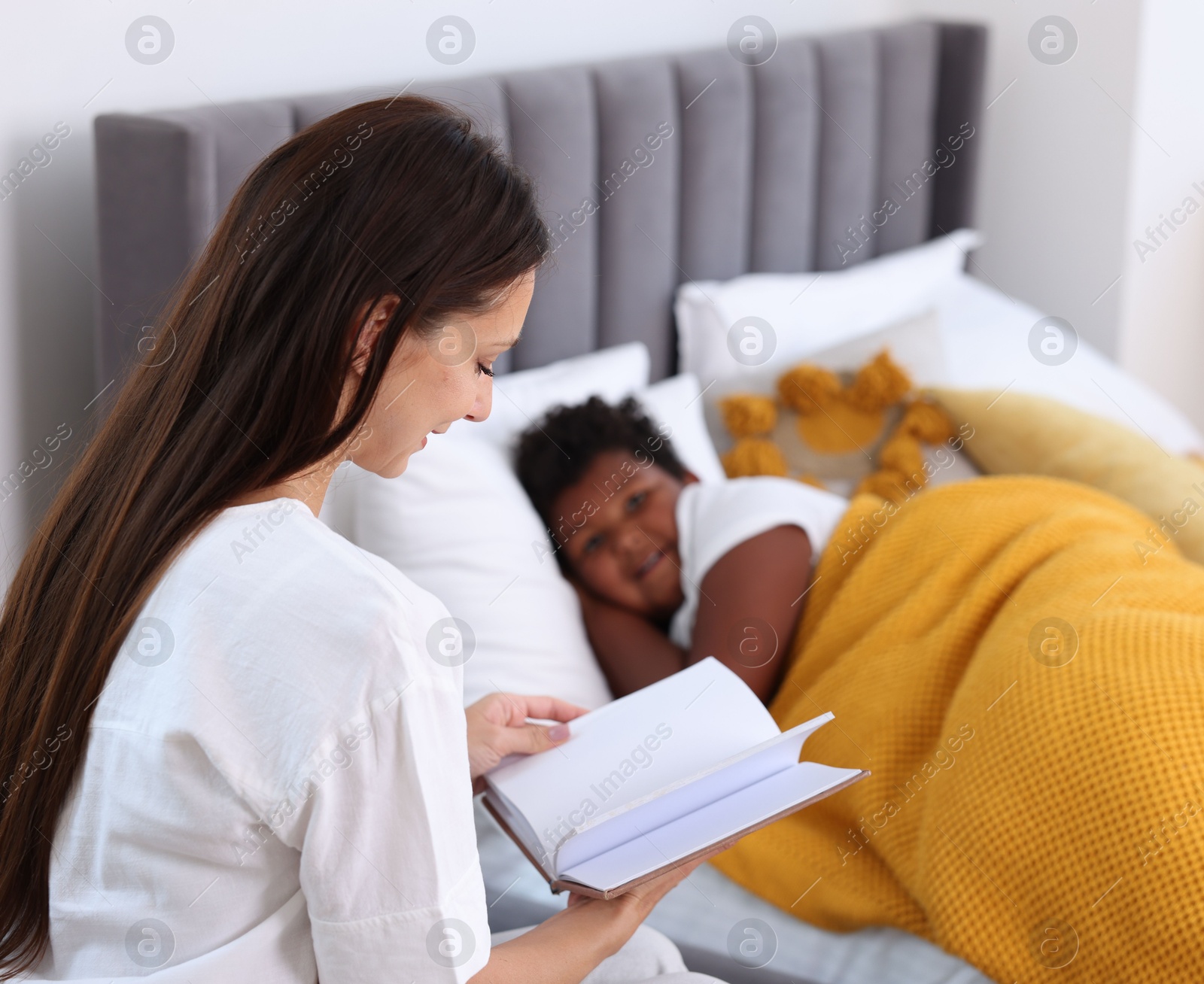 Photo of Mother reading fairy tale to her son at home, selective focus