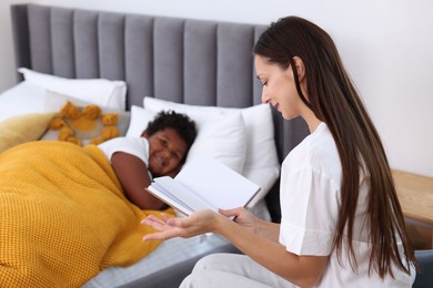 Photo of Mother reading fairy tale to her son at home, selective focus