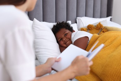 Photo of Mother reading fairy tale to her son at home, closeup