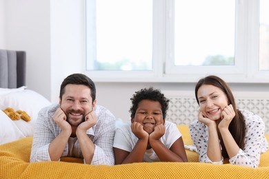 Photo of Adoption. Happy parents and their son on bed at home