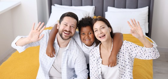 Photo of Adoption. Happy parents and their son on bed at home