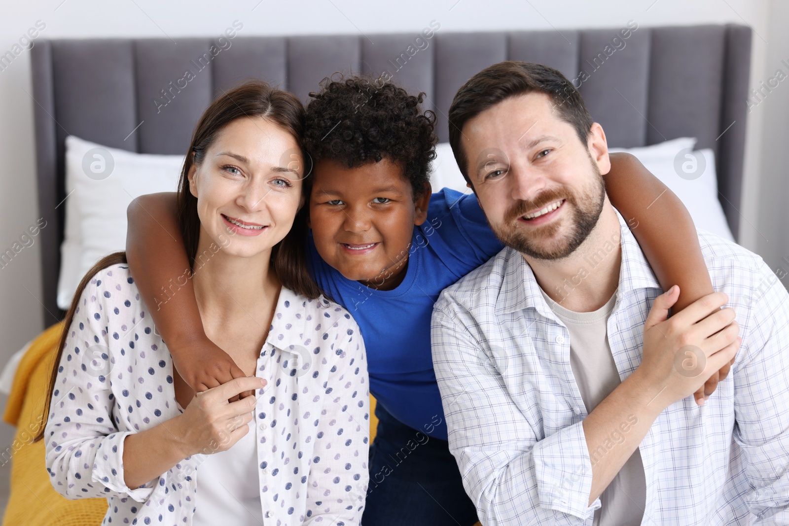 Adoption. Happy parents and their son on bed at home Photo of Adoption. Happy parents and their son on bed at home