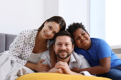 Photo of Adoption. Happy parents and their son on bed at home