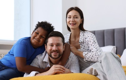 Photo of Adoption. Happy parents and their son on bed at home