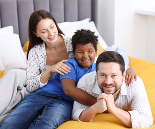 Photo of Adoption. Happy parents and their son on bed at home