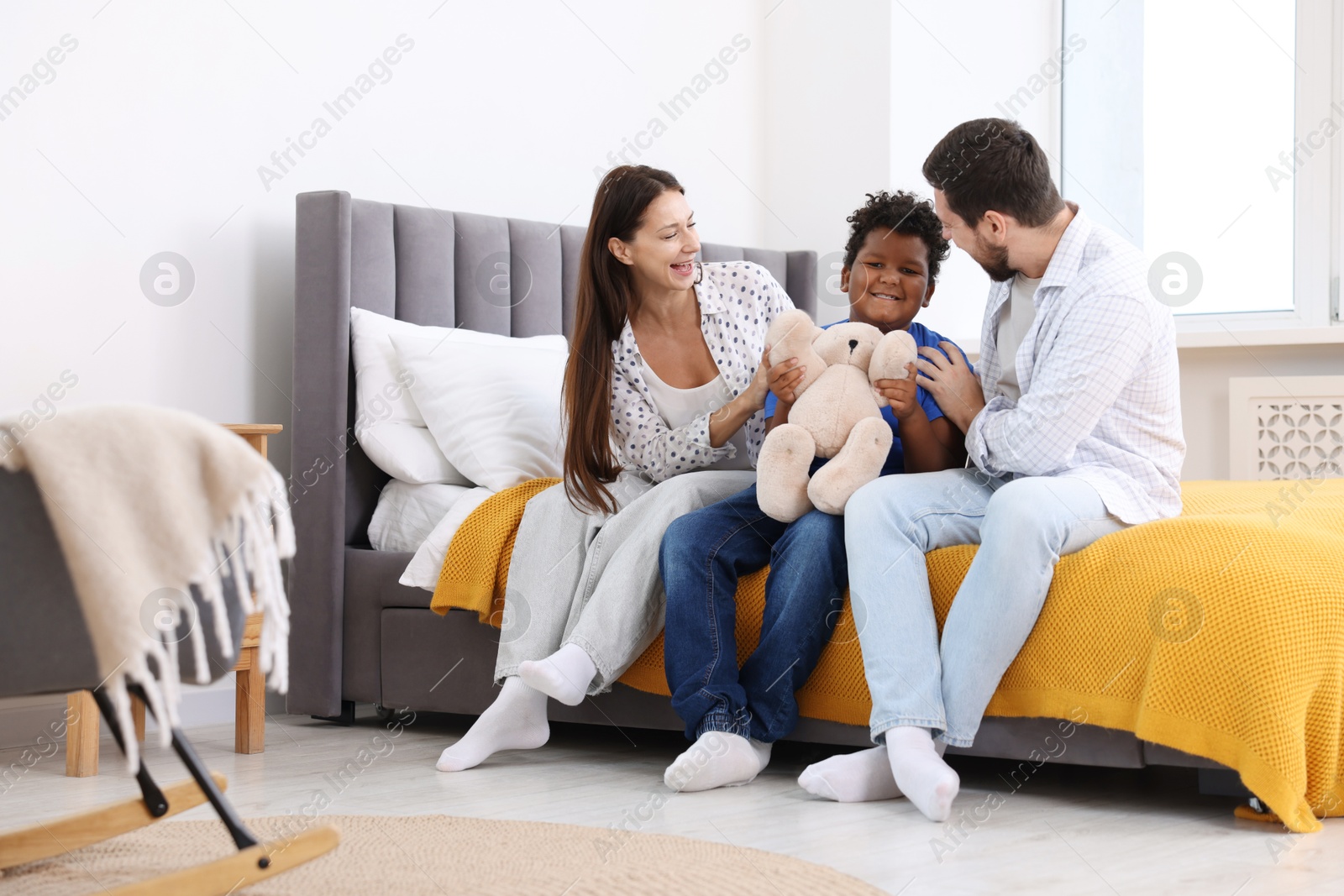 Photo of Adoption. Happy parents and their son on bed at home