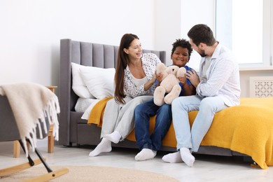 Photo of Adoption. Happy parents and their son on bed at home