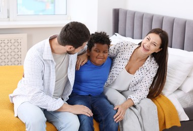 Photo of Adoption. Happy parents and their son on bed at home