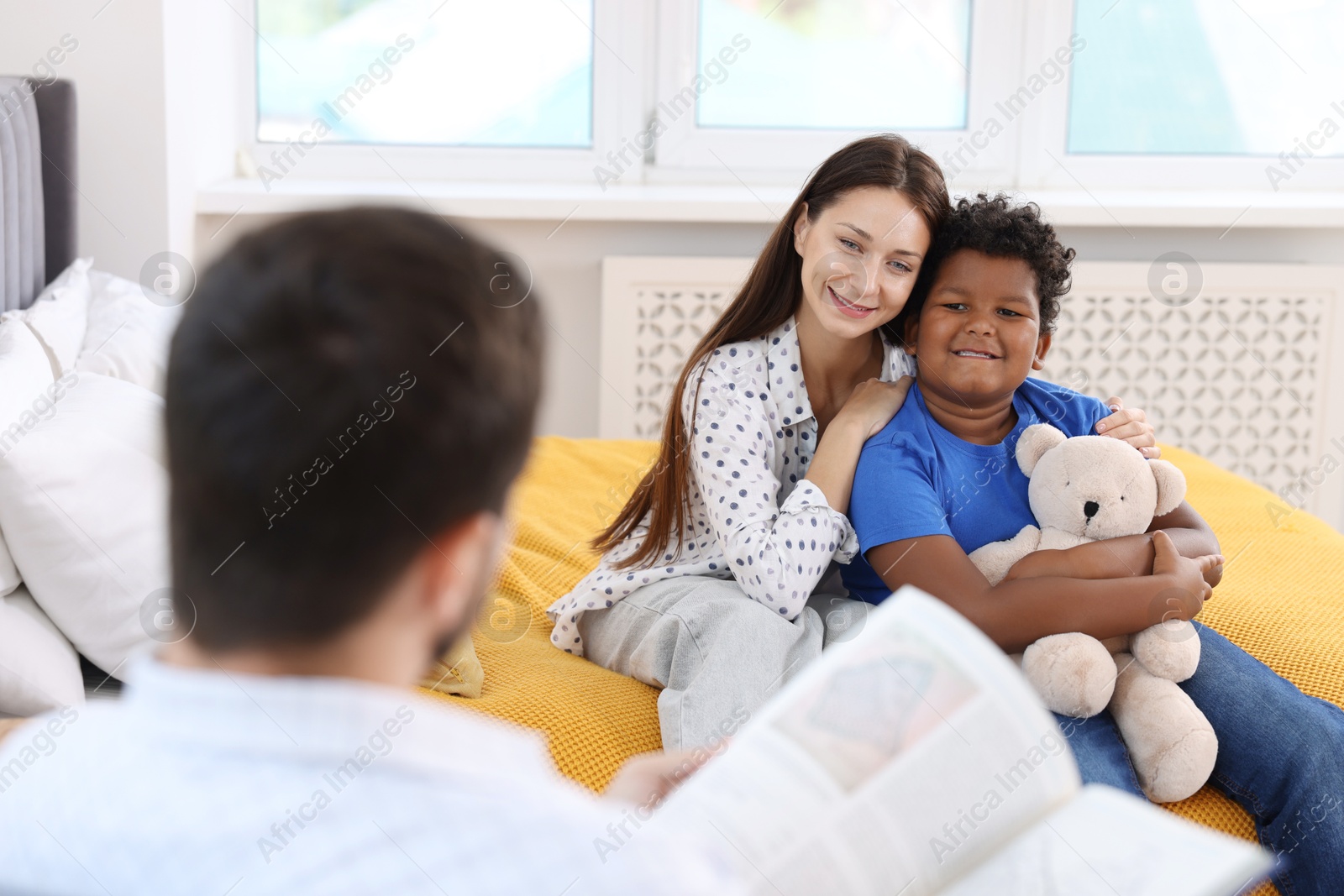 Photo of Father reading story to his family at home, selective focus