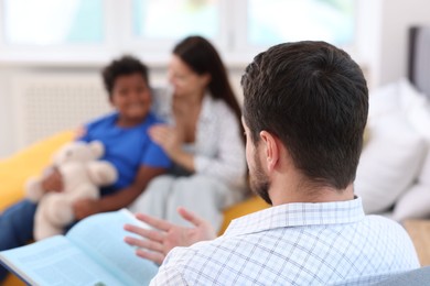 Photo of Father reading story to his family at home, selective focus