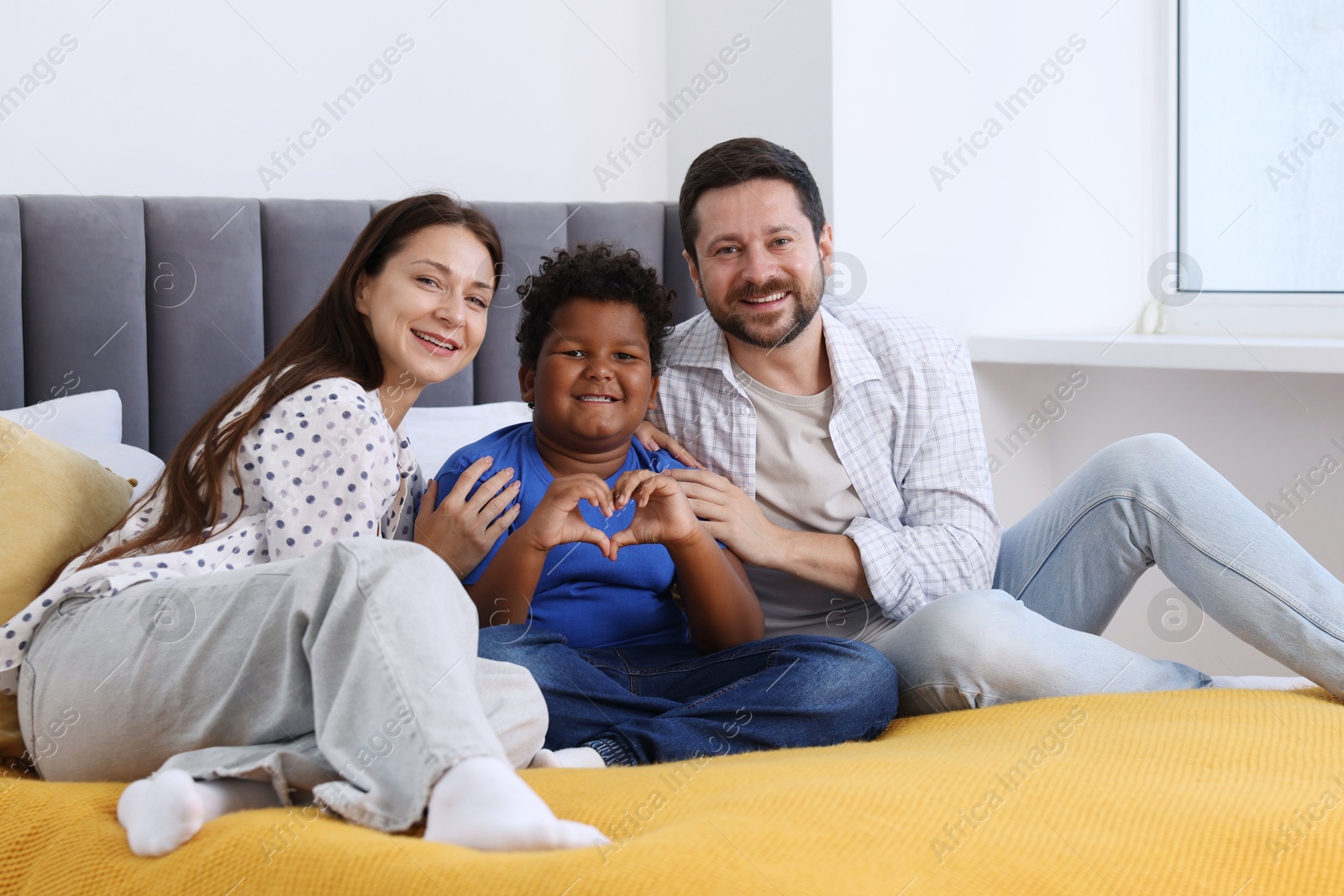 Photo of Adoption. Happy parents and their son on bed at home
