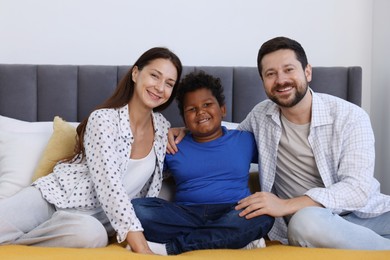 Photo of Adoption. Happy parents and their son on bed at home