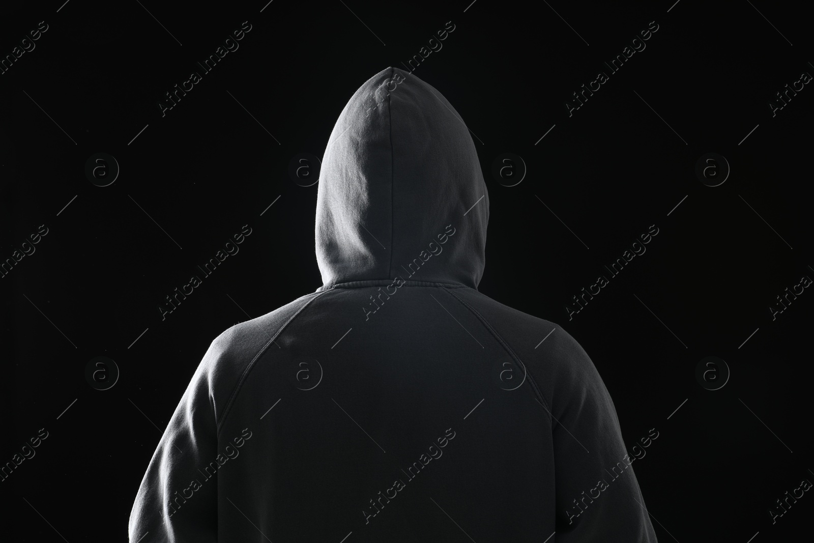 Criminal in hood on dark background, back view Photo of Criminal in hood on dark background, back view