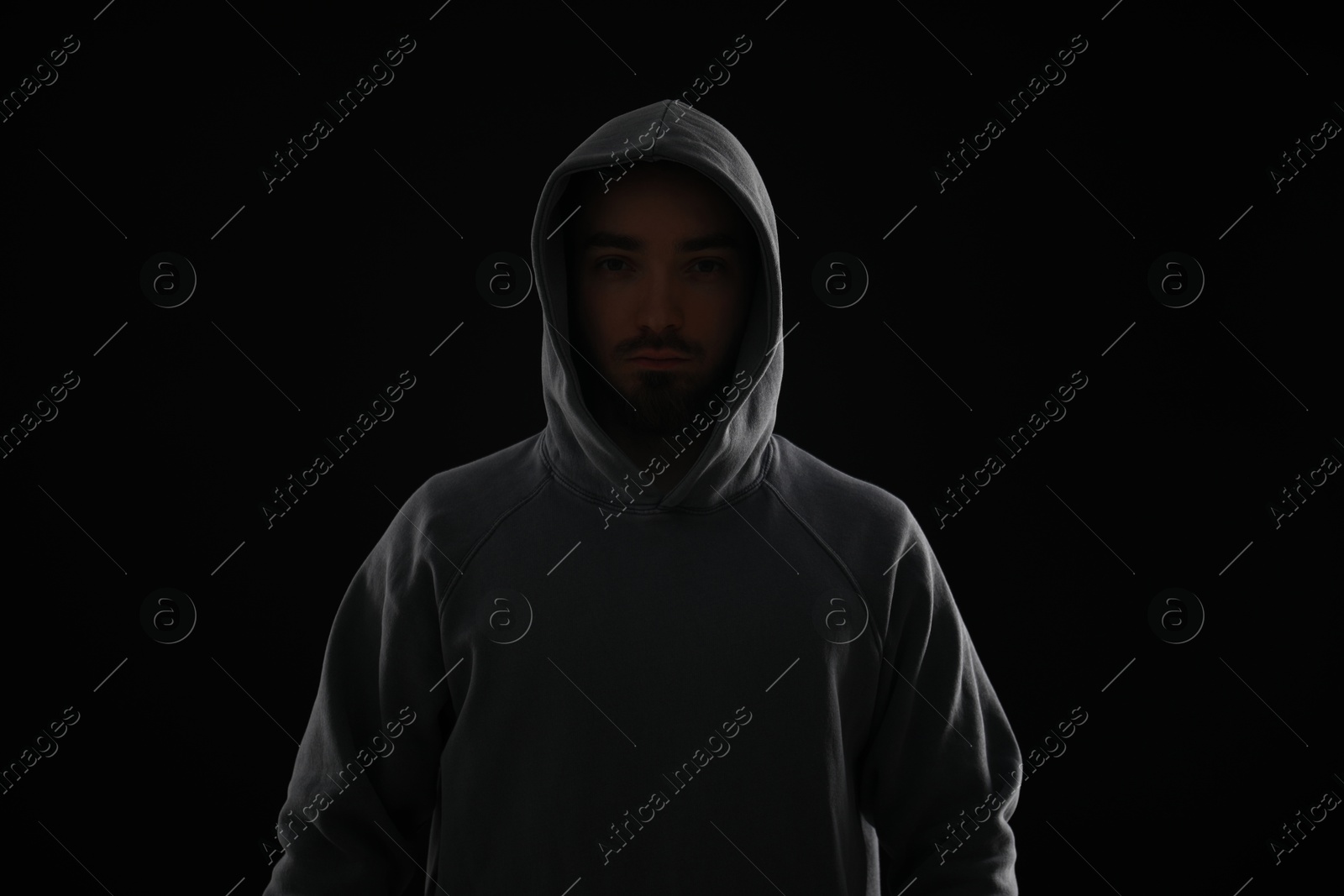 Criminal man in hood on dark background Photo of Criminal man in hood on dark background