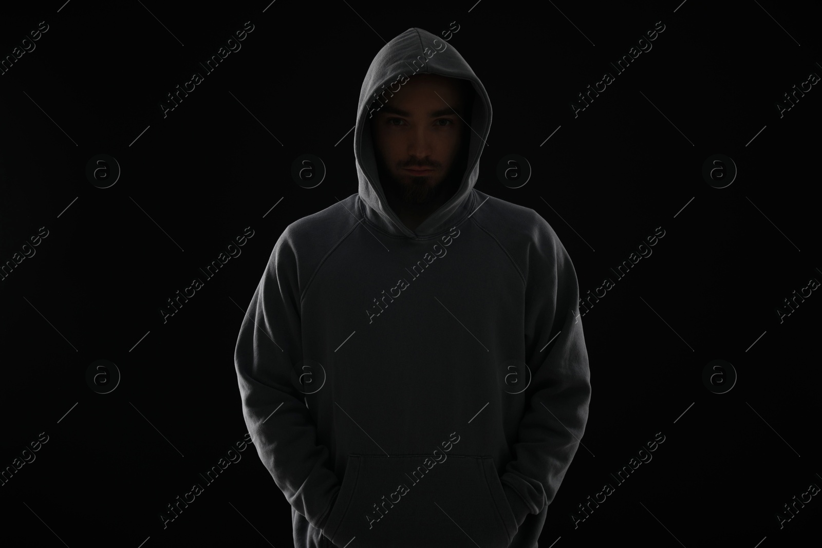 Criminal man in hood on dark background Photo of Criminal man in hood on dark background