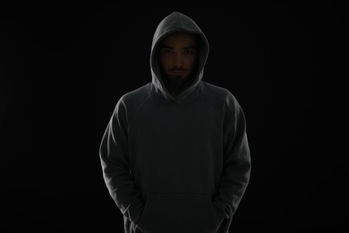 Photo of Criminal man in hood on dark background
