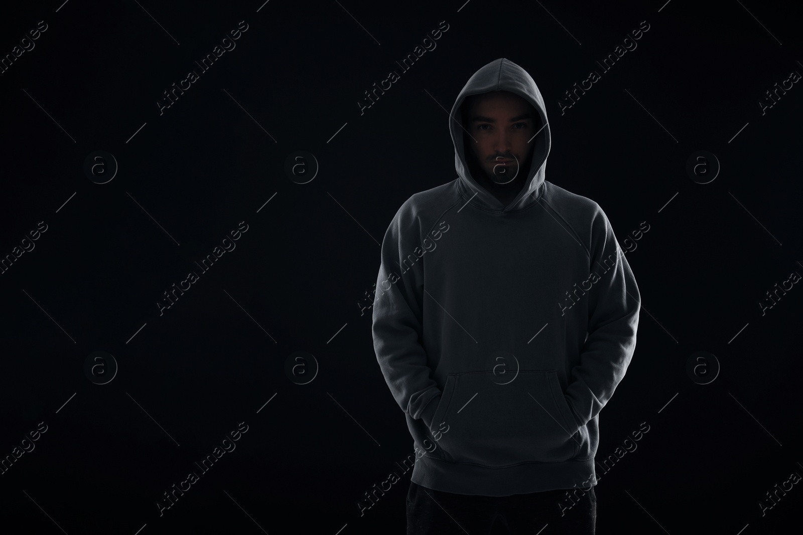 Criminal man in hood on dark background. Space for text Photo of Criminal man in hood on dark background. Space for text