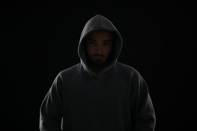 Photo of Criminal man in hood on dark background
