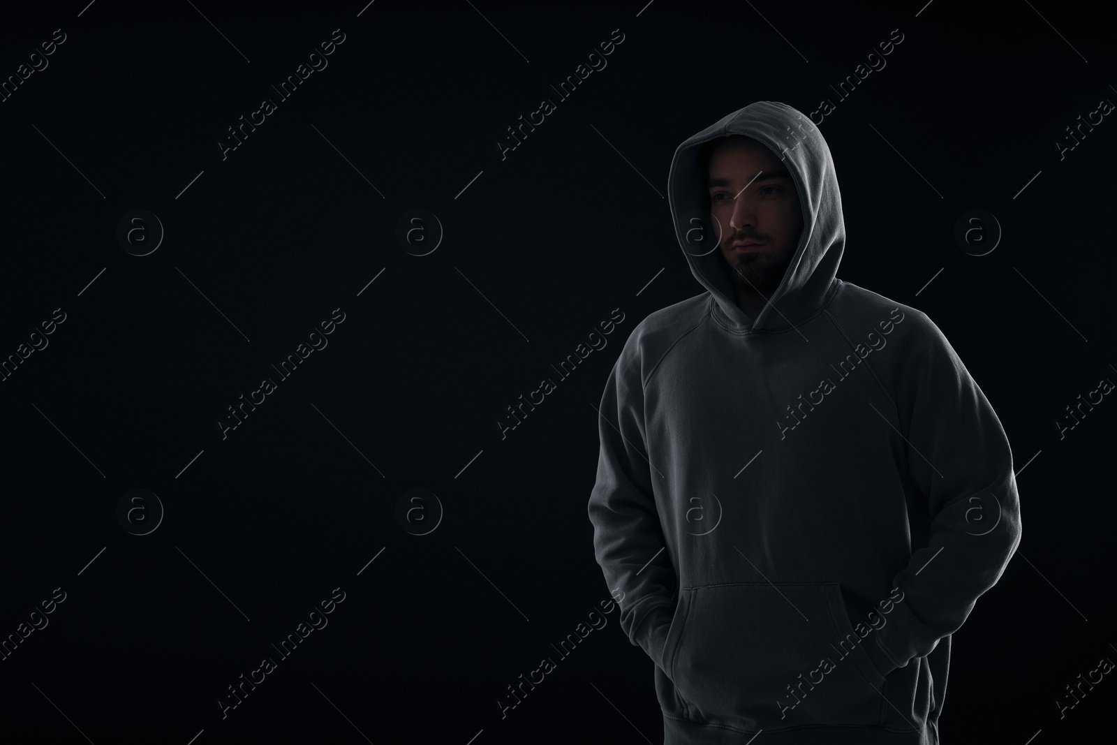 Criminal man in hood on dark background. Space for text Photo of Criminal man in hood on dark background. Space for text
