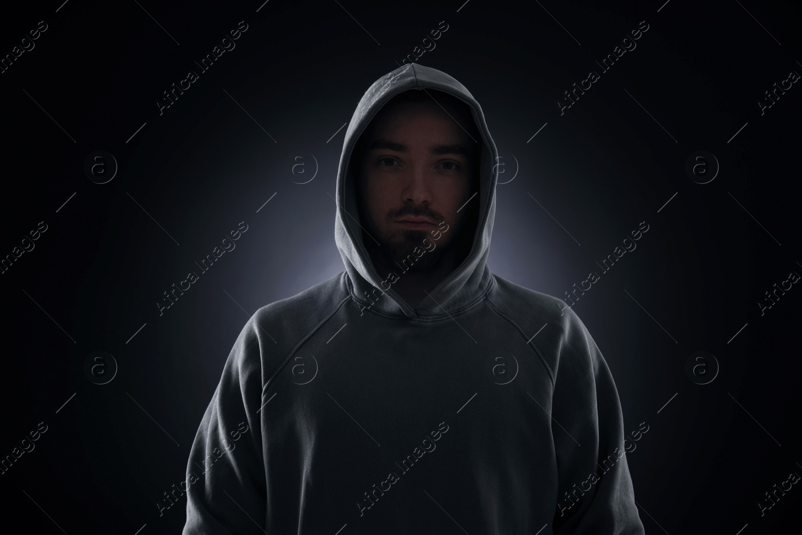 Criminal man in hood on dark background Photo of Criminal man in hood on dark background