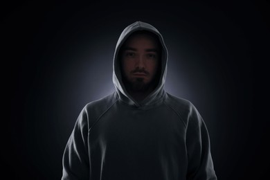 Photo of Criminal man in hood on dark background