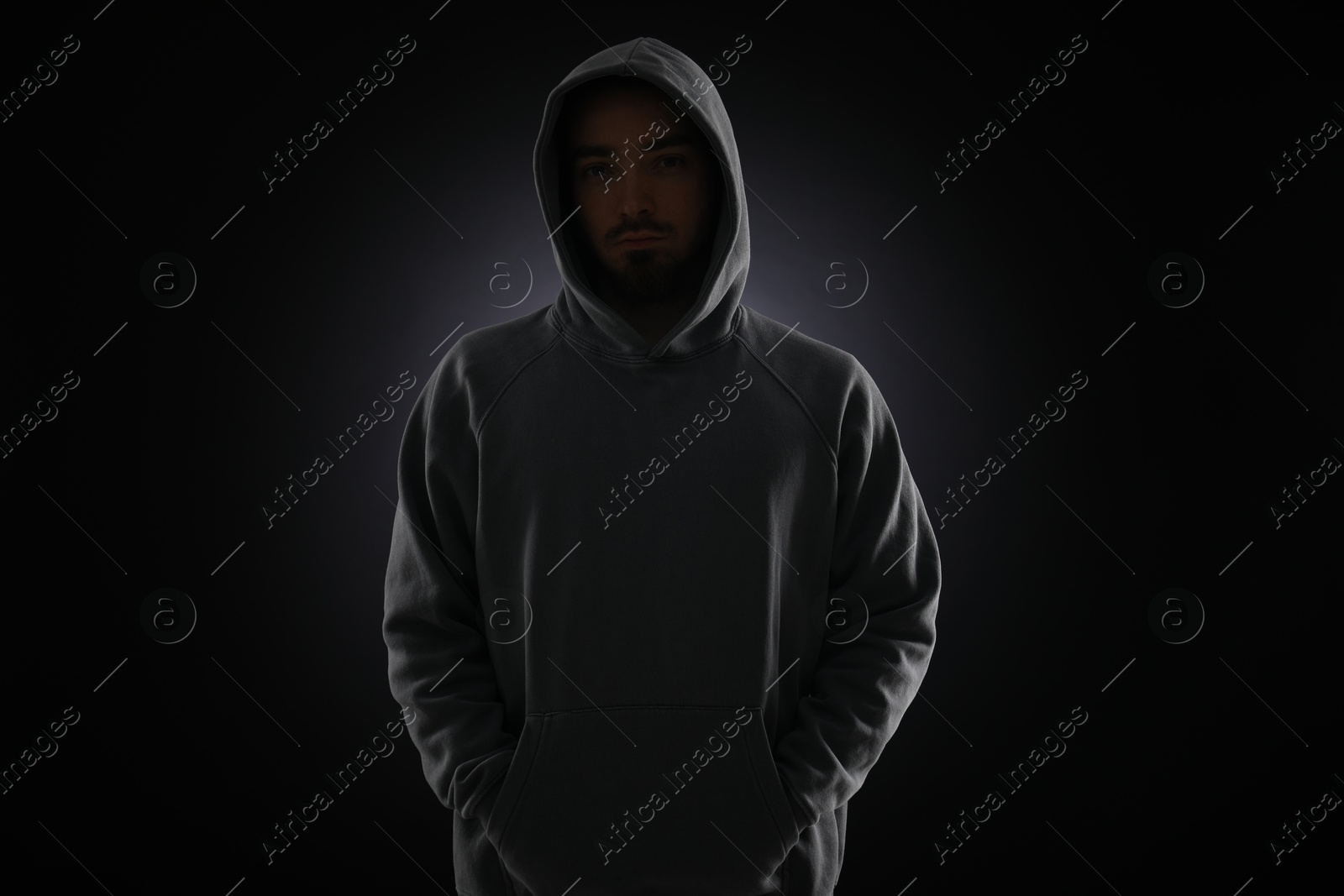 Criminal man in hood on dark background Photo of Criminal man in hood on dark background