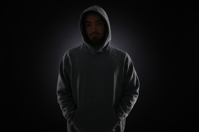 Photo of Criminal man in hood on dark background