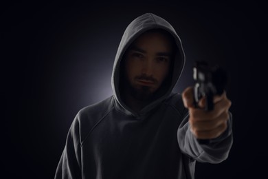Photo of Criminal with gun on dark background, selective focus
