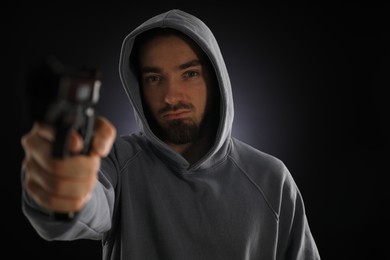 Photo of Criminal with gun on dark background, selective focus
