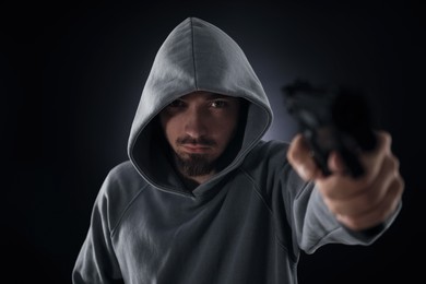 Photo of Criminal with gun on dark background, selective focus