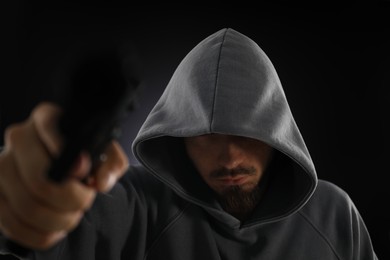 Photo of Criminal with gun on dark background, selective focus