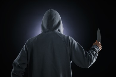 Photo of Criminal with knife on dark background, back view