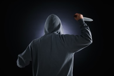 Photo of Criminal with knife on dark background, back view