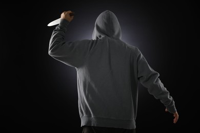 Photo of Criminal with knife on dark background, back view