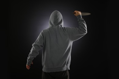 Photo of Criminal with knife on dark background, back view